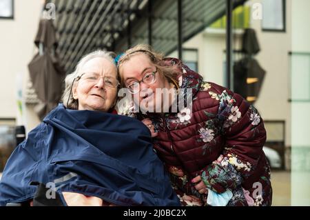 83 year old senior woman in a wheelchair embrased by her 39 year old Down Syndrome daughter, Tienen Stock Photo