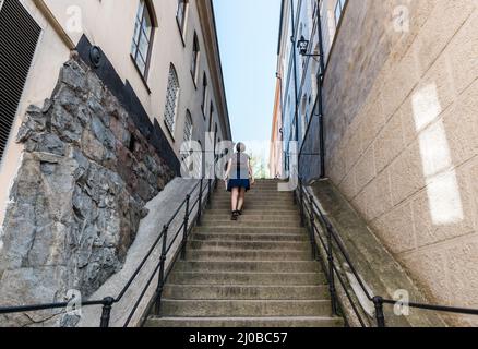 Stockholm, Sweden - 07 24 2019- Attractive tourist woman in summer skirt walking up a stair in Gamla Stan - Old Town Stock Photo