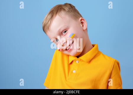 Portrait of a cute boy with drawn flags on his cheeks of Ukraine and Poland. concept of friendship of peoples Stock Photo