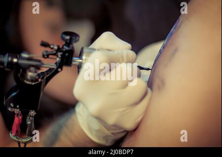 Master tattoo draws the blue paint on the clients tattoo Stock Photo