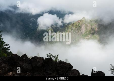 Look from high up in the mountain into deep valley through clouds Stock Photo