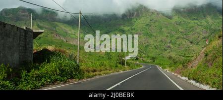 Asphalt road leading in green mountain with cloud on cape verde island Stock Photo