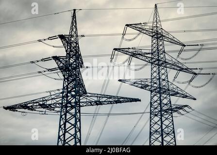 Power pylons of overhead power line against dramatic sky Stock Photo