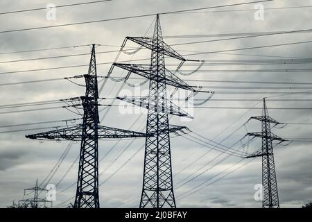 Power pylons of overhead power line against dramatic sky Stock Photo