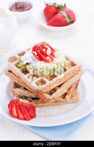 Waffles with wholewheat flour and fruits on a white plate on a blue napkin Stock Photo