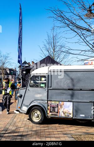 Epsom Surrey London UK, March 17 2022, Workman With Yellow Vest Using Mobile Phone Walking Past Closed Pop Up Food Van Stock Photo