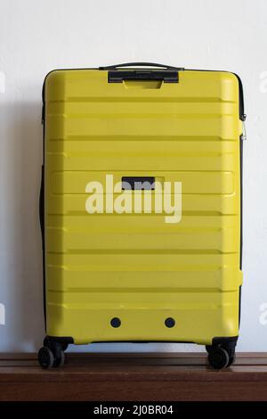 Yellow suitcase against a white wall.  Stock Photo