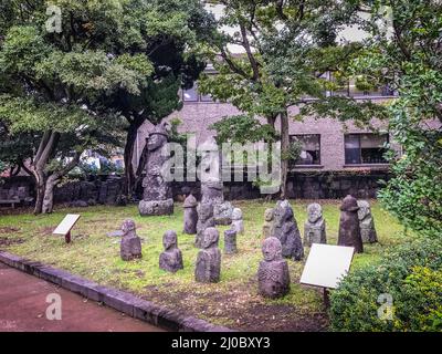 Group of Stone idols (Dolharubang, the grandfather stones) in Jeju Mokgwana, the oldest remaining building in Jeju for former ce Stock Photo