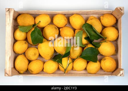 Lemons in a wooden box at the market ready for sale, cut out on white Stock Photo