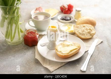 Continental breakfast sweet and salty with buns, cooked egg and a cup of coffee on rustic stone, copy space, selected focus, narrow depth of field Stock Photo