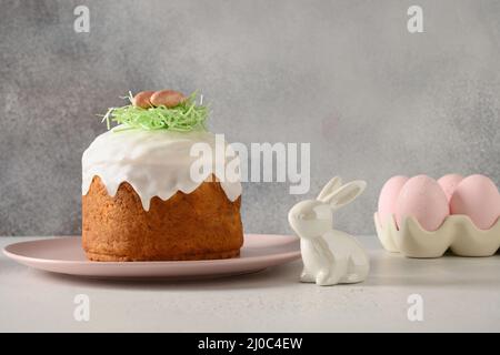 Homemade traditional Easter cake, easter rabbit, pink eggs on gray background. Stock Photo