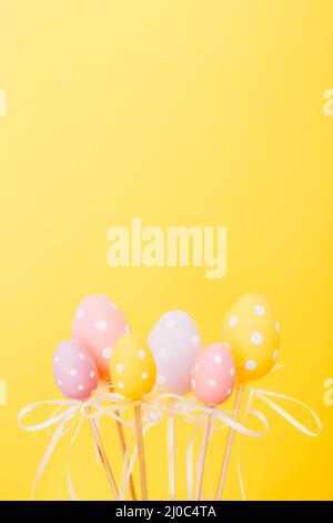 Colorful Easter eggs on sticks on yellow background Stock Photo