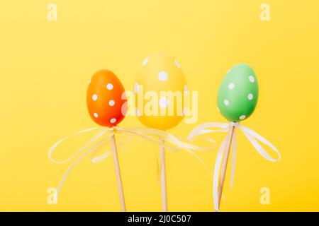 Colorful Easter eggs on sticks on yellow background Stock Photo