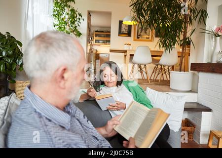 Senior retired couple relaxing reading books in the living room at home Stock Photo