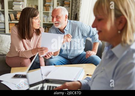 Senior couple discussing care funding contract with financial advisor on computer Stock Photo