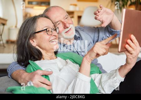 Senior pensioner couple having fun video chatting with family on tablet computer at home Stock Photo