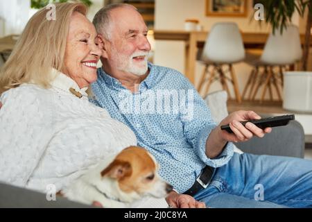 Senior couple on the sofa at home using the remote control as relaxed tv viewers Stock Photo