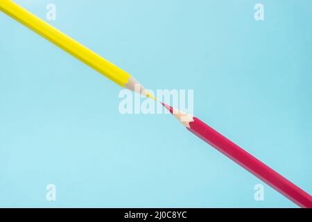 Business concept - yellow and red color pencil floating on blue paper background against each other. It's symbol of fight. Stock Photo