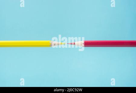 Business concept - yellow and red color pencil floating on blue paper background against each other. It's symbol of fight. Stock Photo