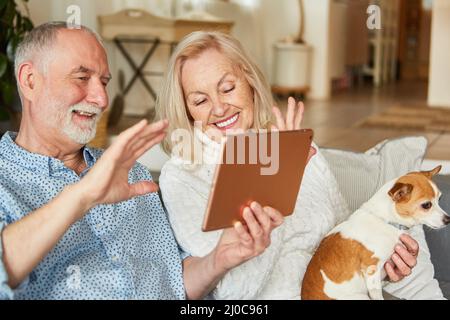 Happy retired senior couple video chatting with family on tablet computer Stock Photo