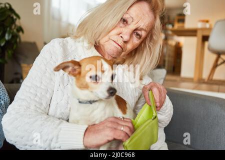 Sad senior woman with small dog showing her empty wallet as a concept of poverty in old age Stock Photo