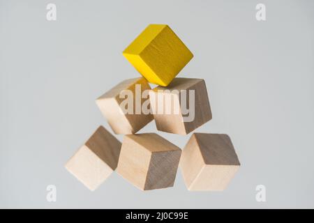 Business concept - Abstract geometric real floating wooden cubes layout like triangle on grey background and it's not 3D render. Stock Photo