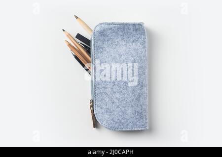 Top view of grey fabric pencil case with lot of pens on white background desk for mockup Stock Photo