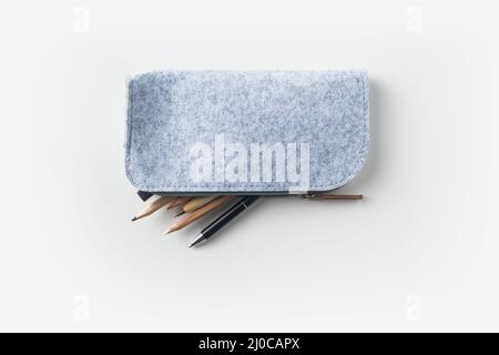 Top view of grey fabric pencil case with lot of pens on white background desk for mockup Stock Photo