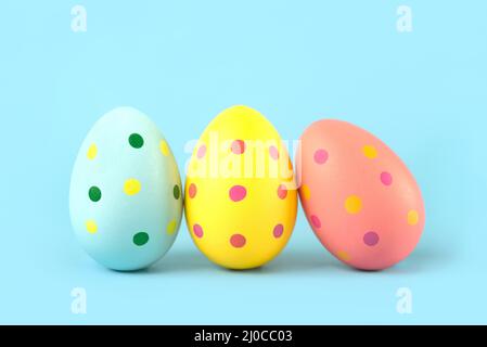 Happy Easter. Close-up of three colored easter painted eggs over blue background Stock Photo