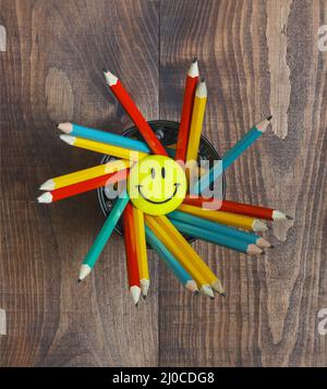 Multicolored pencils in a stand on a wooden school desk Stock Photo