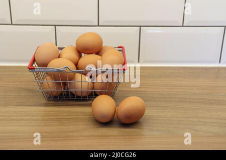 Basket of eggs, with two eggs outside of the basket Stock Photo