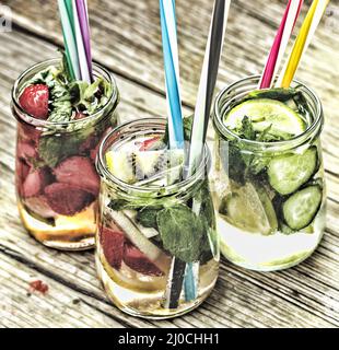 A variety of cold drinks in small bottles with pieces of fruit wooden background Stock Photo