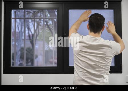 Man installing frosted window vinyl on wet window glass. Stock Photo