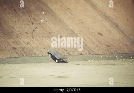 Old used skateboard on grey asphalt in the skatepark Stock Photo