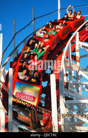 Thrill seekers scream as they head into a descent on the Giant Dipper Roller coaster in Santa Cruz California Stock Photo