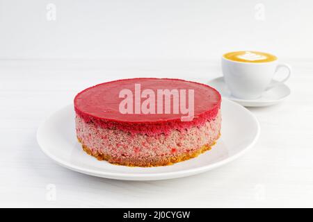 Homemade raspberry and strawberry cheesecake and cup of coffee cappuccino on white wooden table. Copyspace. Stock Photo