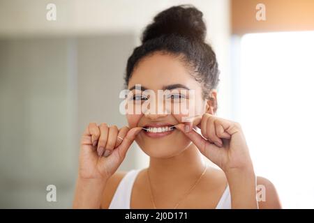 Healthy habits, healthy teeth. Shot of an attractive and happy young woman flossing her teeth. Stock Photo