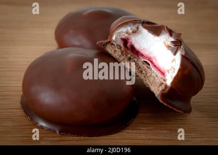 Sweet confectionery and marshmallow sweet delights concept with marshmallows coated in milk chocolate on a wooden rustic background Stock Photo