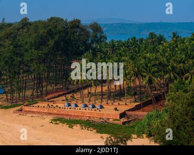 Tents surrounded by coconut trees for trekkers for camping near sea shore in Malvan, India Stock Photo