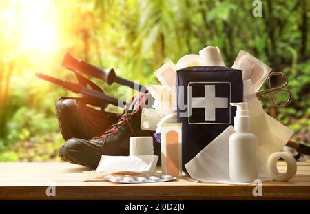 Basic portable first aid equipment for leisure nature sports events on wooden table and background of trees. Horizontal composition. Front view. Stock Photo