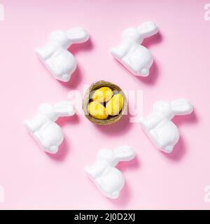 White rabbits and yellow Easter eggs on a pink background. Easter decoration concept Stock Photo
