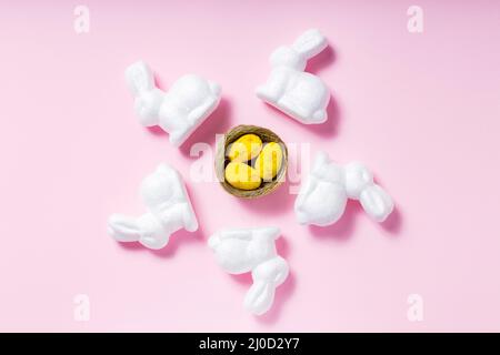 White rabbits and yellow Easter eggs on a pink background. Easter decoration concept Stock Photo