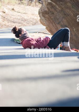 Beautiful outdoorsy woman lies on road outdoors in climbing park Stock Photo