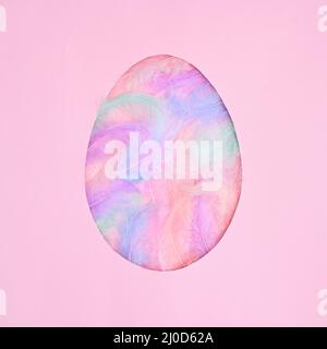 Egg shape frame with natural colorful feathers on pastel pink background. Flat lay creative Easter concept Stock Photo