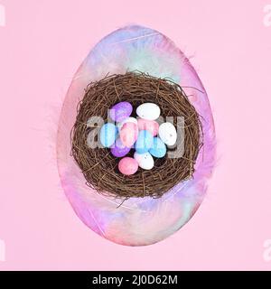 Egg shape with neast with eggs on pastel pink background. Flat lay creative Easter concept Stock Photo