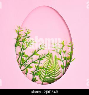 Easter creative concept. Egg shape with natural green plants on pastel pink background. Flat lay Stock Photo