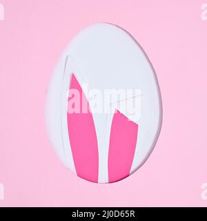 Easter creative concept. Egg shape with bunny ears on pastel pink background. Flat lay Stock Photo