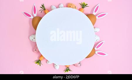 Easter arrangement decorations with round white paper card and copy space on pastel pink background. Flat lay Stock Photo