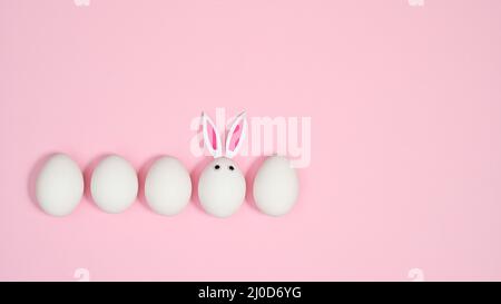 Creative composition with white eggs and one with rabbit ears on pastel pink background. FLat lay creative Easter copy space. Stock Photo