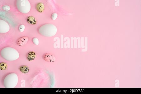 Romantic pastel pink background with white natural eggs quail eggs and feathers. Creative copy space flat lay. Easter composition Stock Photo